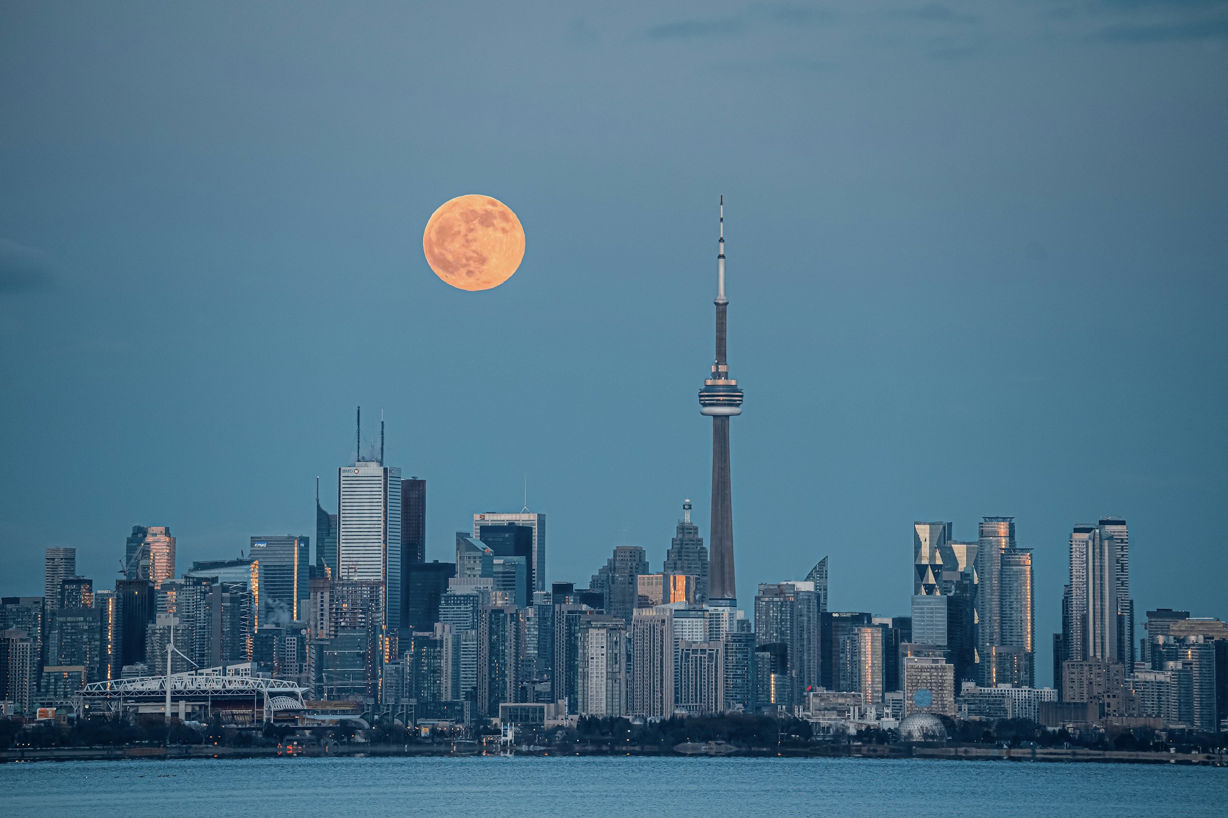 Toronto skyline and the CN Tower at blue hour under a full moon